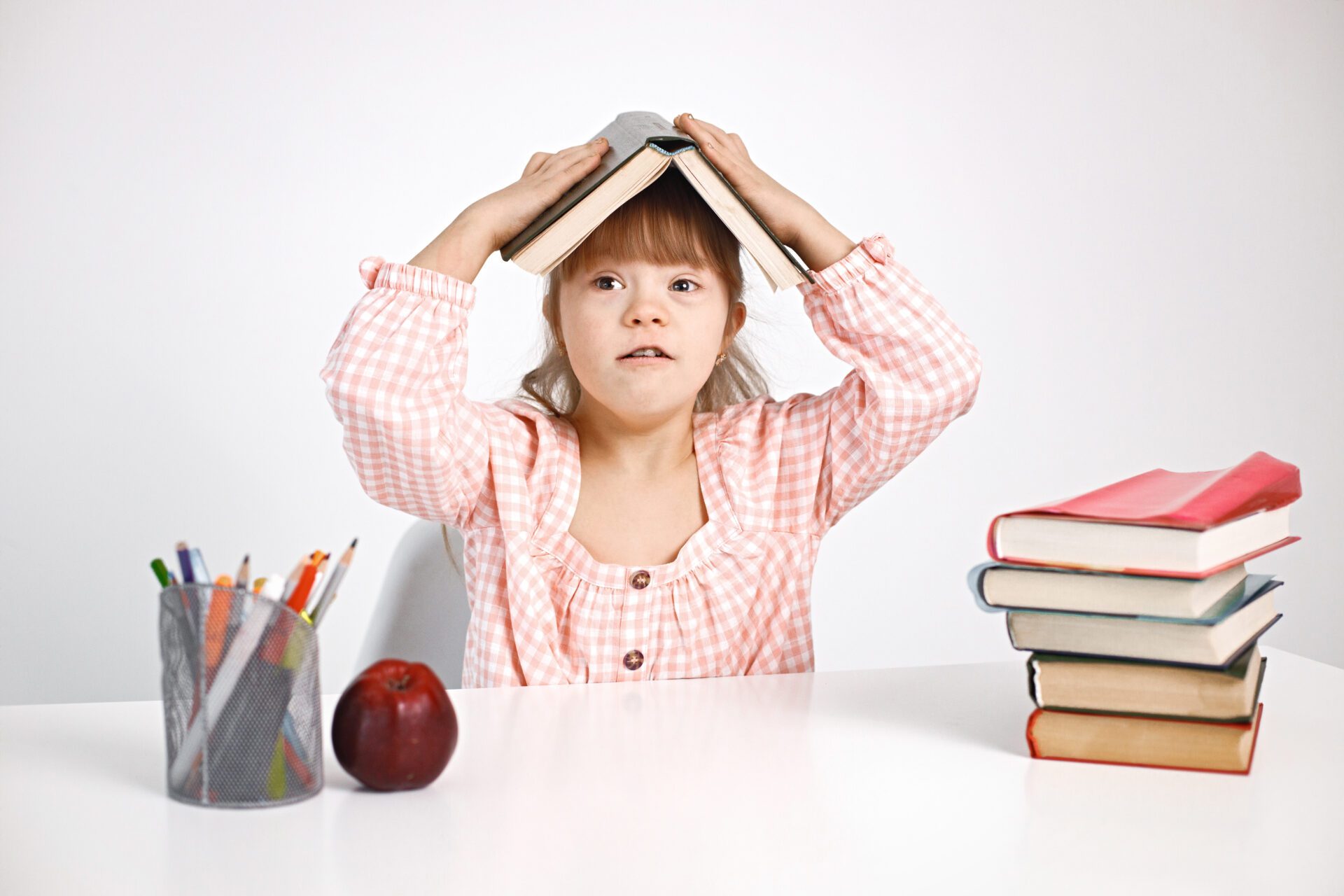 إقليم تازة .. افتتاح مركز للأشخاص ذوي الاحتياجات الخاصة 1 girl with down syndrome sitting at desk and holding book on her head