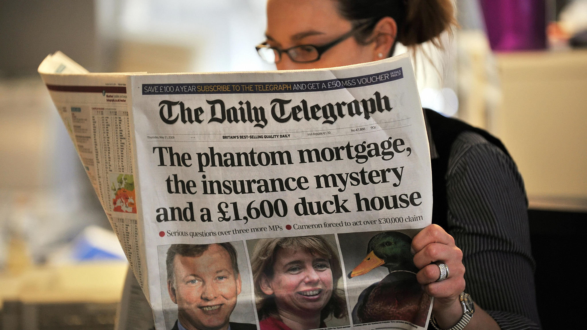 A woman reads a copy of the Daily Telegr