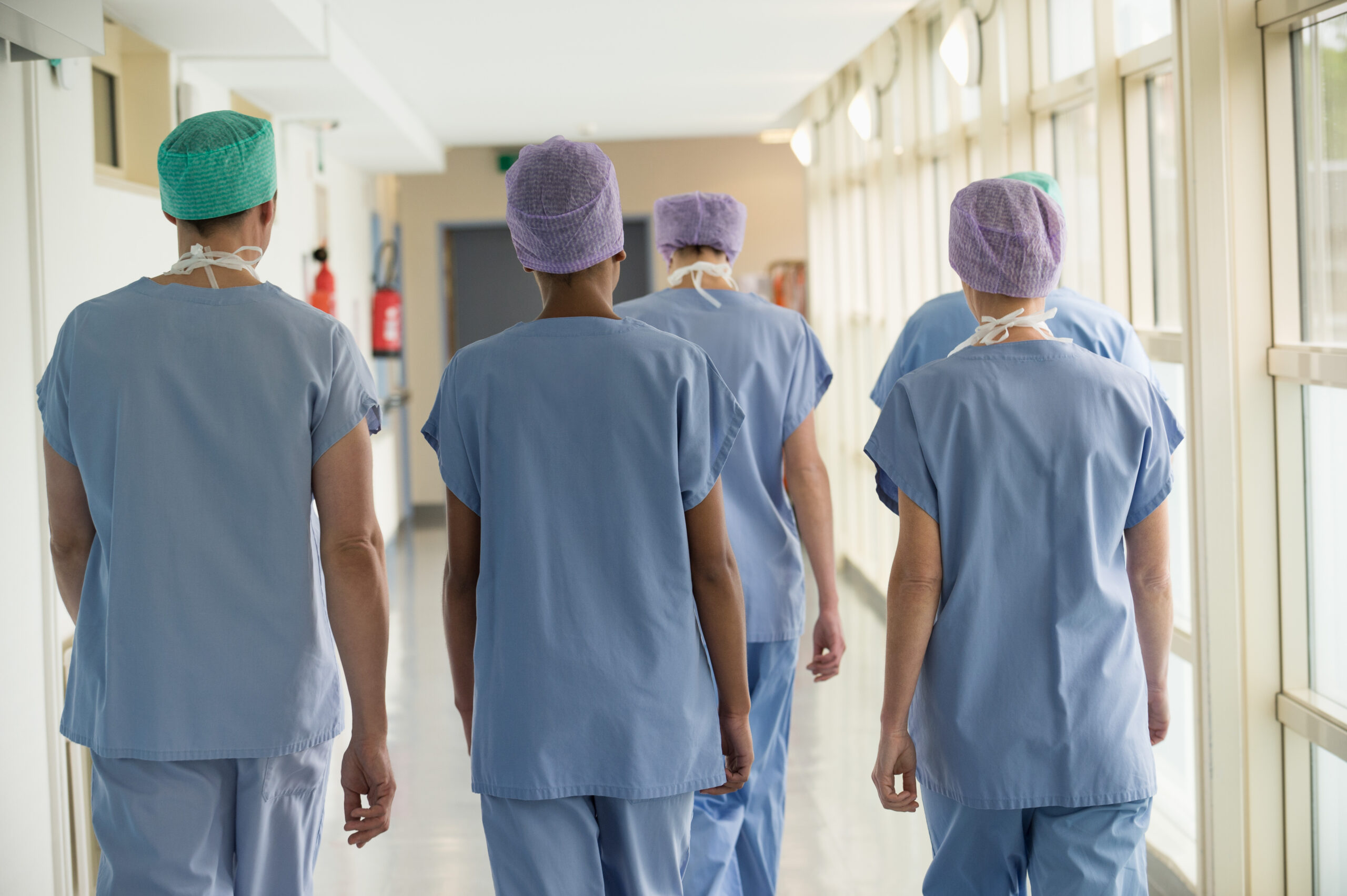 Rear view of a medical team walking in the corridor of a hospital
